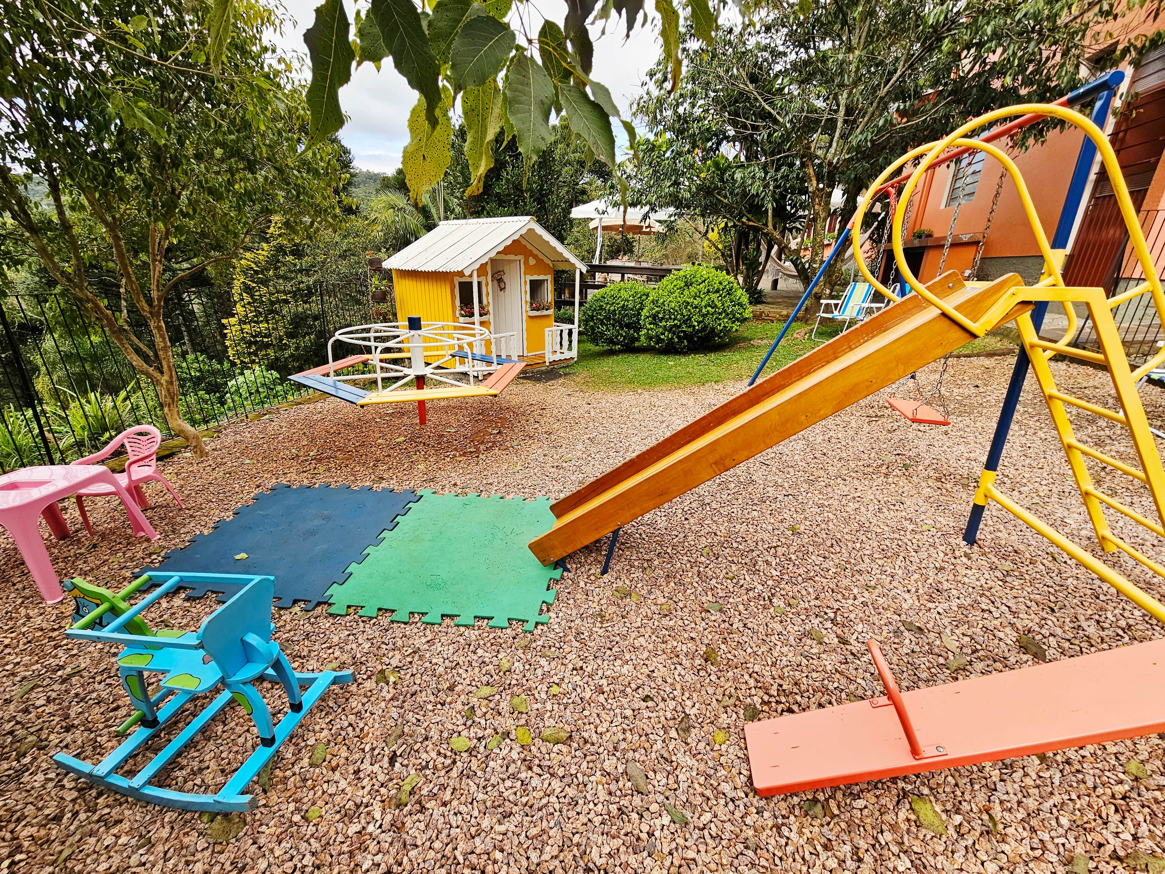 Área kids com escorregador, gira-gira, balanço e casinha à beira da Serra Gaúcha