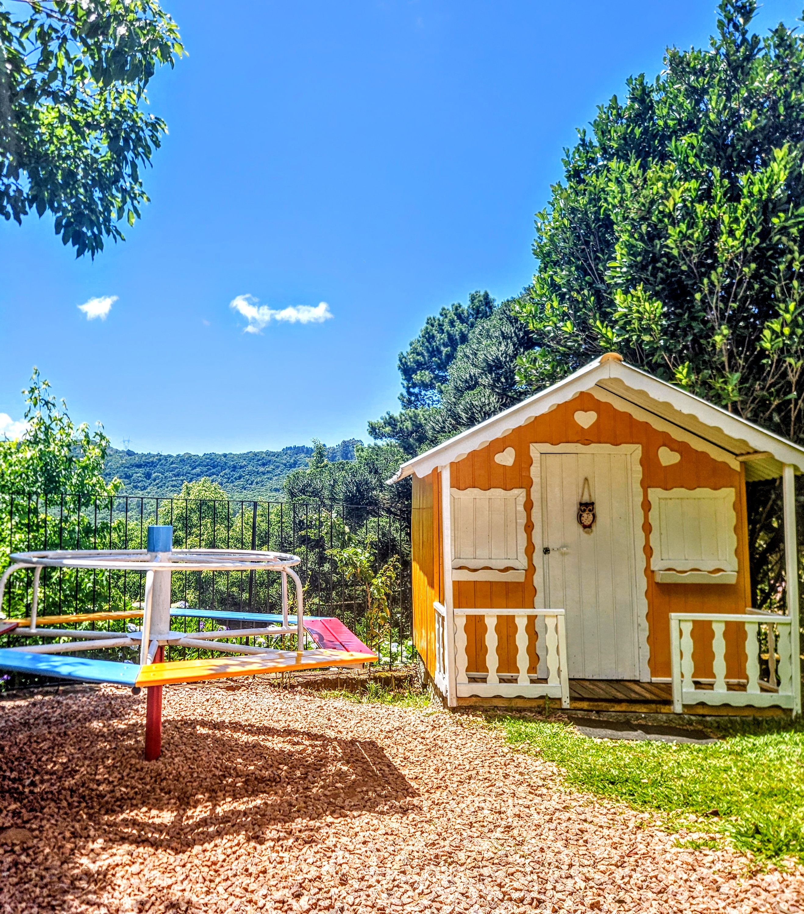 Casinha laranja da área kids com vista panorâmica para as montanhas da Serra Gaúcha e céu azul
